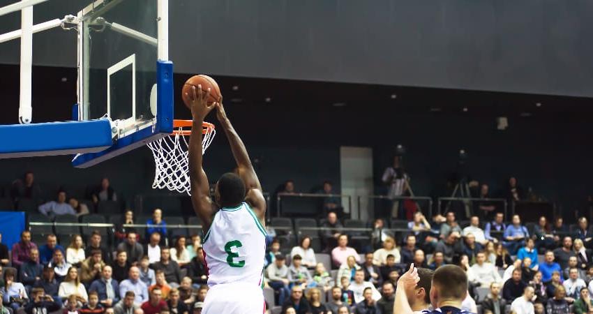 A basketball player lands a lay-up in a packed stadium